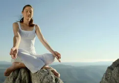 Mujer joven meditando en acantilado