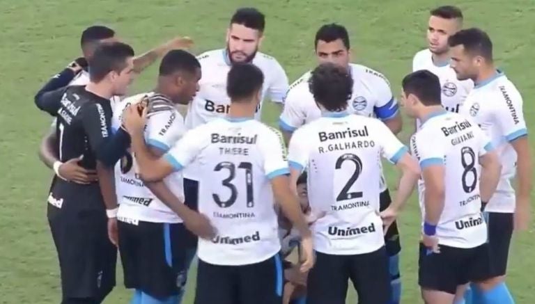 Los jugadores del Gremio en reunión, mientras Douglas orina en el campo