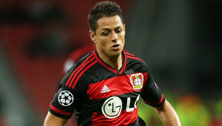 Chicharito conduce el balón en juego del Bayer