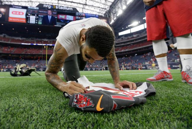 Mike Evans firma su jersey para entregárselo a Arian Foster