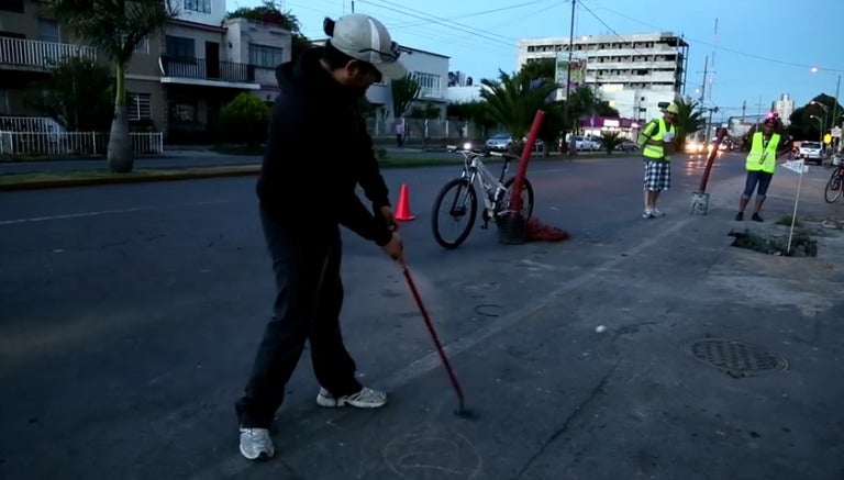 Ciudadano jugando golf en la calle