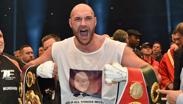 Tyson Fury festeja con los cinturones