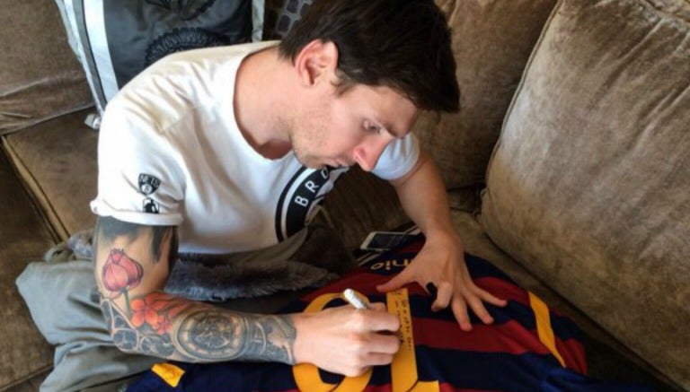 Messi, firmando la playera que obsequió a Ronaldinho