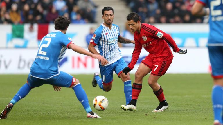 Chicharito toca el balón entre la marca de los defensas