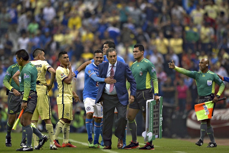 Tomás Boy es contenido por sus jugadores en juego contra América