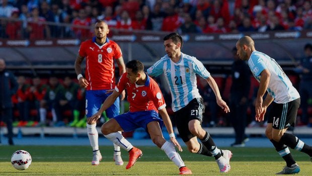 Alexis cubre el balón ante la marca de los argentinos