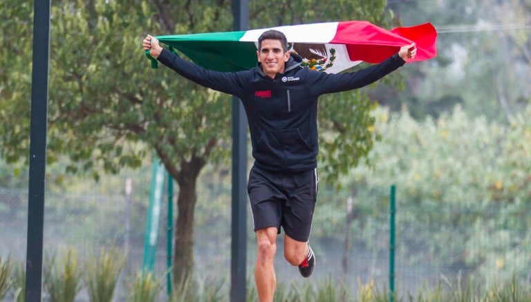 El velocista corre con la bandera a sus espaldas