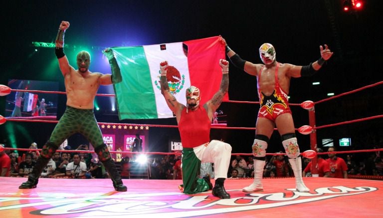 Dragón Azteca Jr., Rey Mysterio y Dr. Warger Jr. con la bandera mexicana