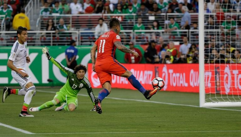 El delantero chileno Vargas define ante la mirada de Ochoa y Moreno