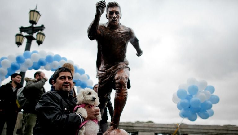 Aficionado argentino posa junto a la estatua de Lionel Messi