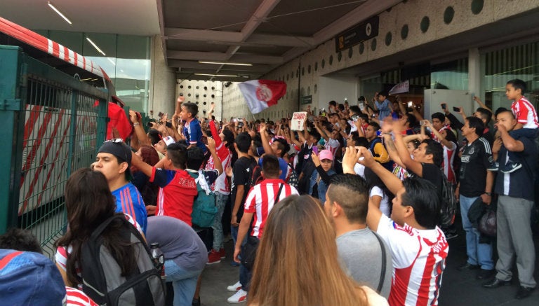 Aficionados de Chivas cantan para apoyar a su equipo en su llegada a la CDMX