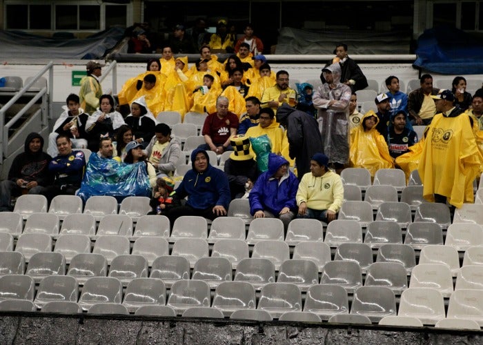 Aficionados se protegen de la lluvia en el estadio