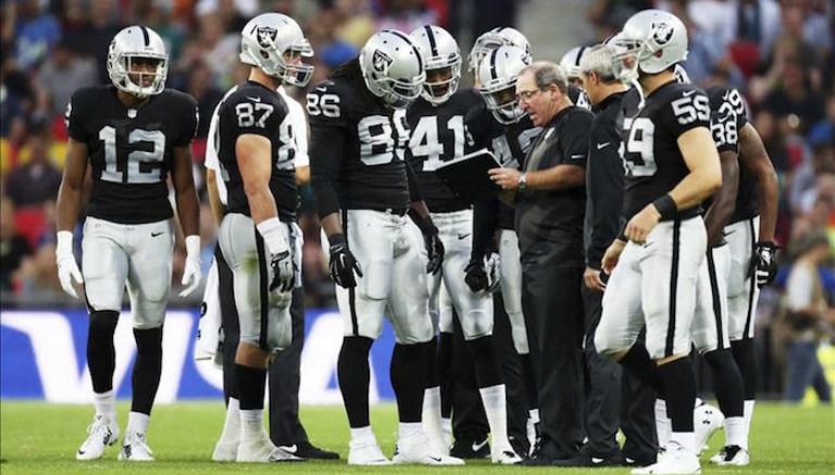 Jugadores de Raiders dialogan durante un encuentro de la NFL