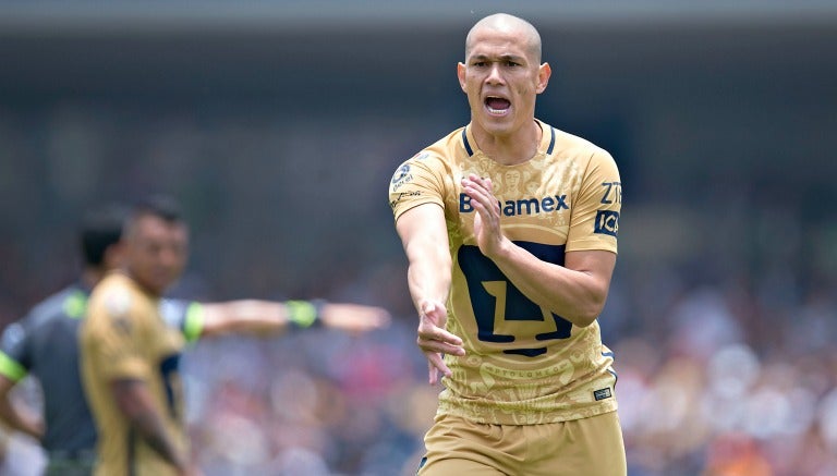 Darío Verón señala una mano en un partido de Pumas