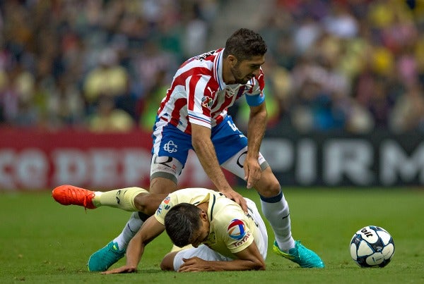 Jair Pereira pelea un balón durante el Clásico con un jugador del América