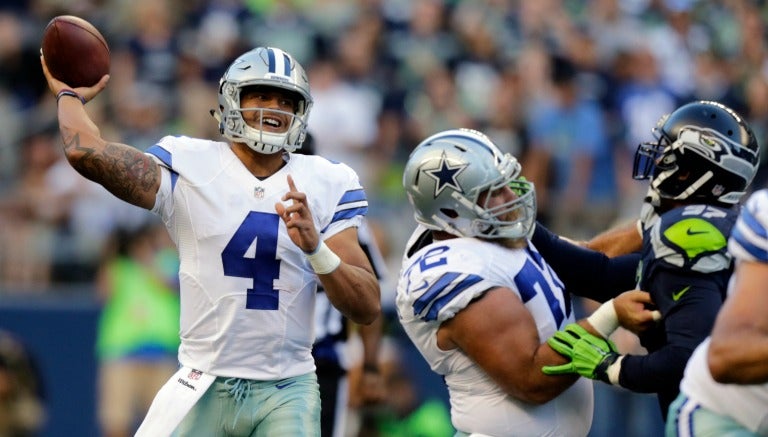 El QB de los Vaqueros de Dallas Dan Prescott intenta lanzar un pase