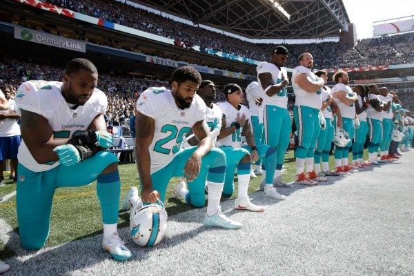 Los jugadores de los Delfines de Miami hincados durante el himno de EU