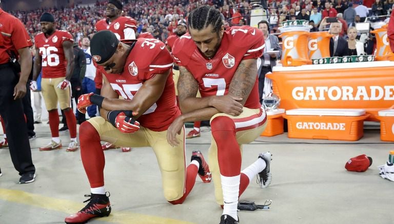 Colin Kapernick (7) y Eric Reid (35) se arrodilan en himno de EU