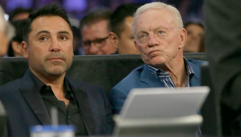 Oscar de la Hoya (izq) y Jerry Jones (der) observan la pelea de Canelo