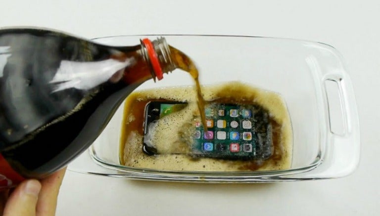 Un iPhone 7 en un refractario con refresco de cola