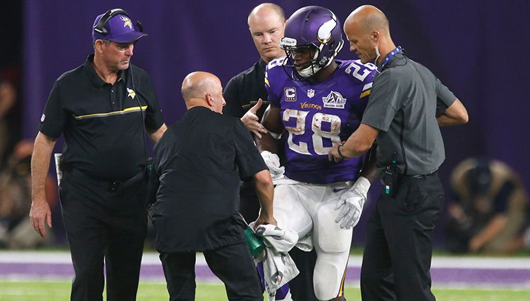 Adrian Peterson es retirado del campo en el juego contra Green Bay