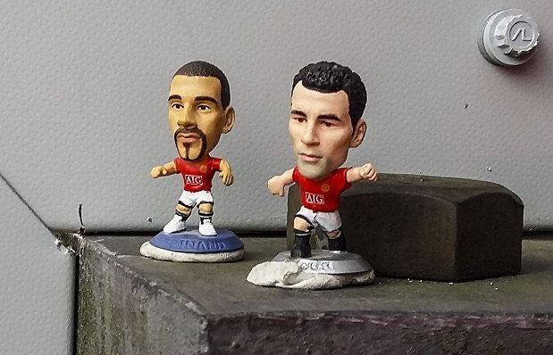 Los figurines de Gigs y Ferdinand en una estructura del estadio del Liverpool