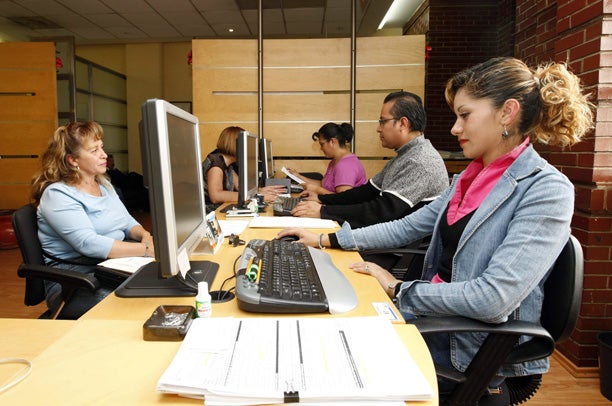 Foto de unos oficinistas trabajando atendiendo a personas