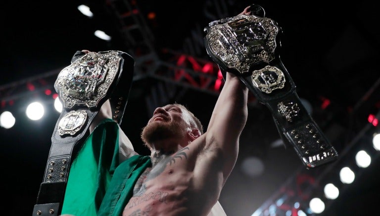 Conor McGregor posa con sus dos campeonatos