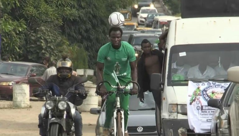 El futbolista nigeriano en bicicleta y con el balón