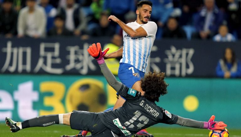 Guillermo Ochoa para el balón ante el defensa del Málaga Juankar Pérez