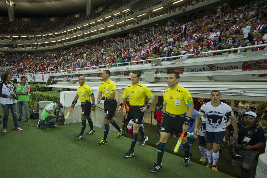 Árbitros salen a la cancha para dar inicio a un encuentro de la Liga MX