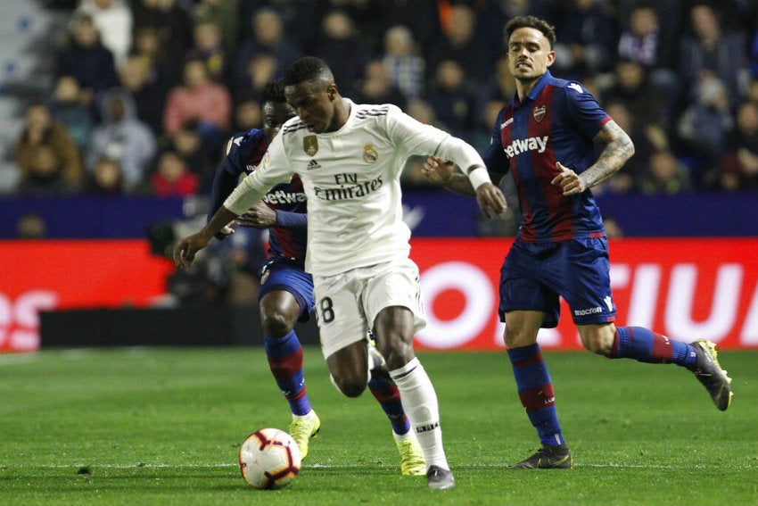 Vinicius conduce el balón, mientras es perseguido por dos rivales 