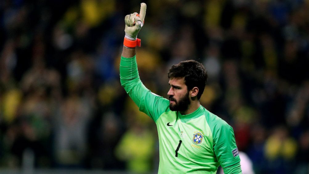 Alisson  levanta el brazo en un juego con Brasil