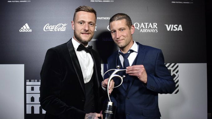 Liam Cooper, capitán del Leeds, y el preparador físico recogen el premio