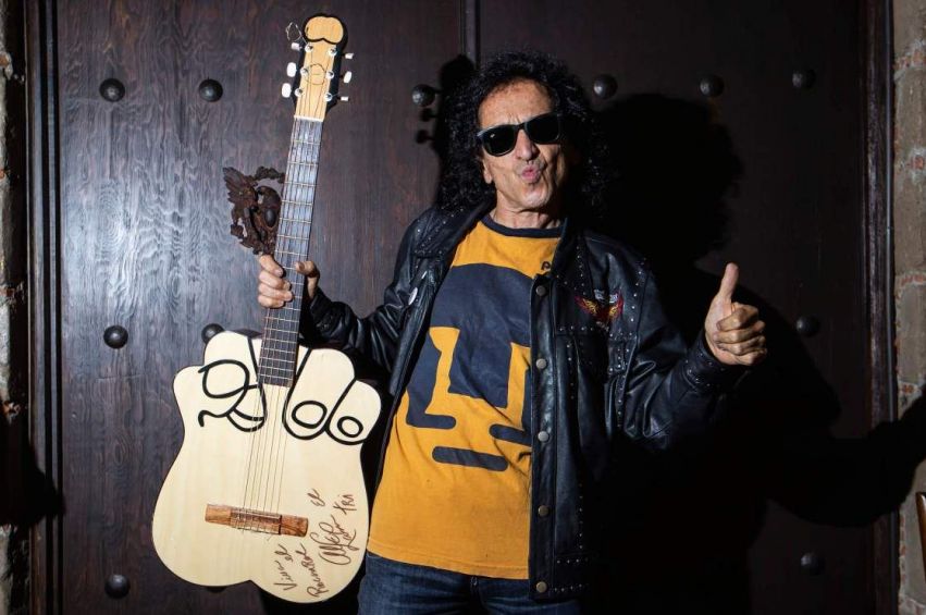 Alex Lora posando con su icónica guitarra y la playera de Pumas