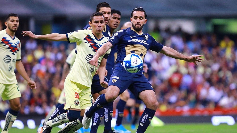 Paul Aguilar y Luis Quintana disputan el balón en un América vs Pumas