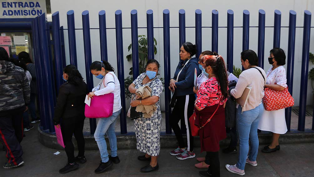 Personas afuera de un hospital con cubrebocas