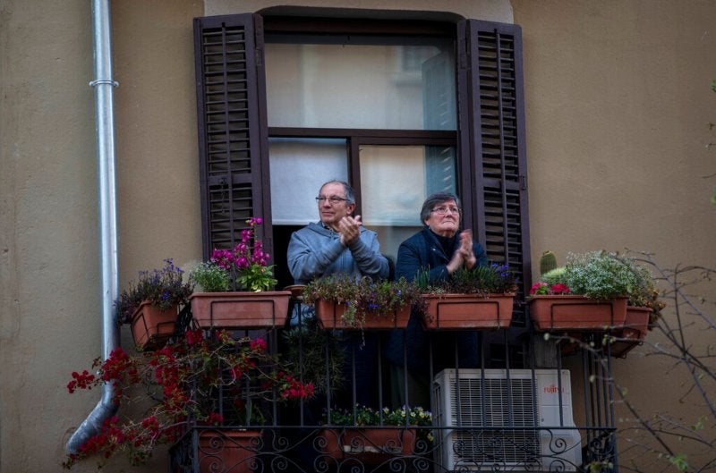 Personas de la tercera edad aplauden desde sus balcones