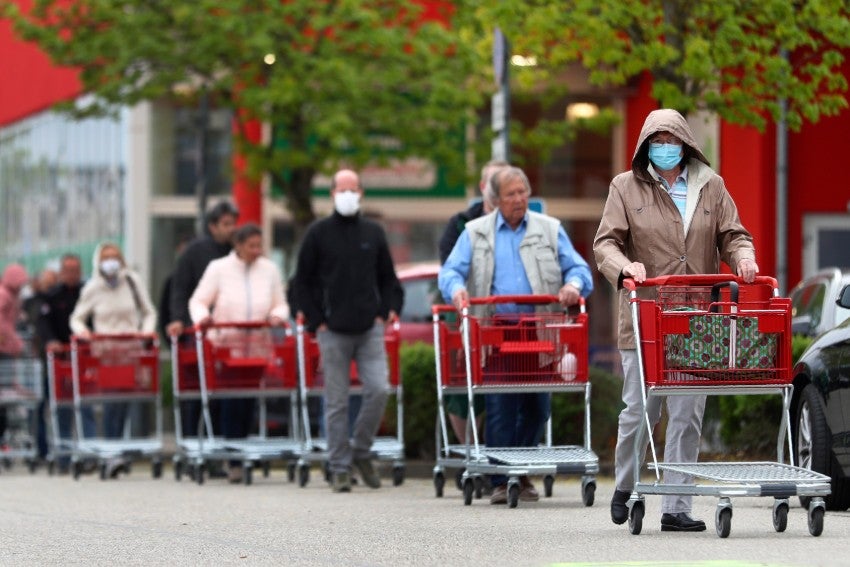 Fila de personas con cubrebocas esperando a entrar a una tienda en Alemania