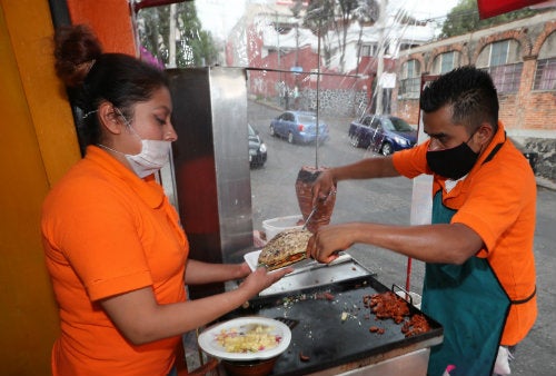 Taqueros preparan comida portando cubrebocas