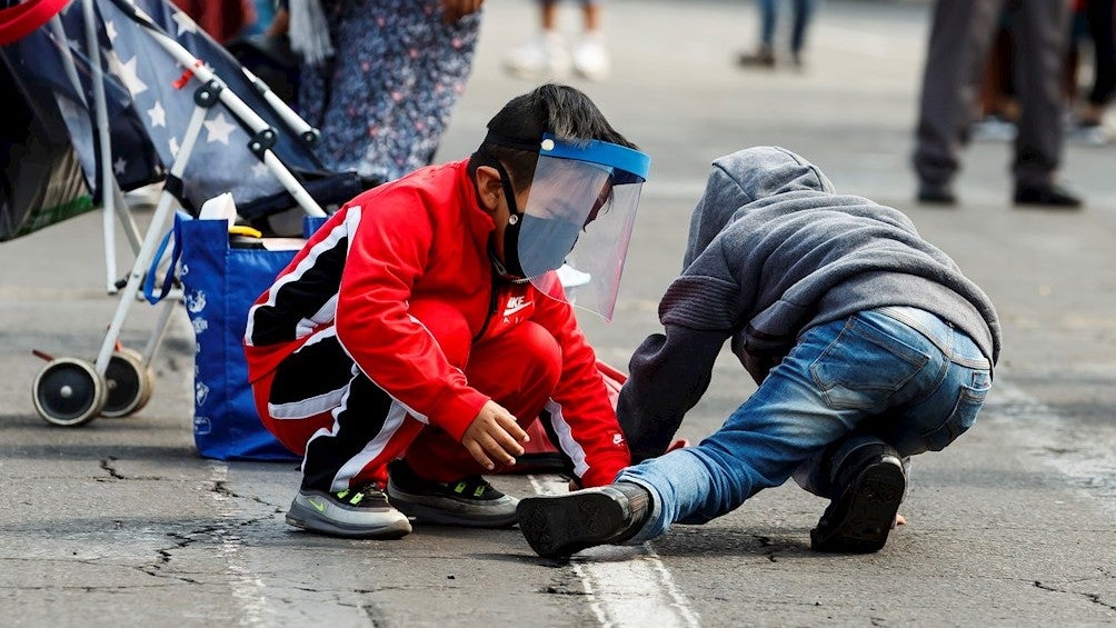 Niños con mascarilla juegan en la calle