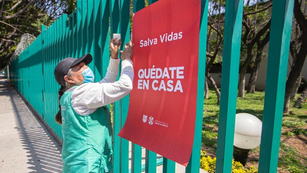 Persona coloca un cartel de 'Quédate en casa' en CDMX