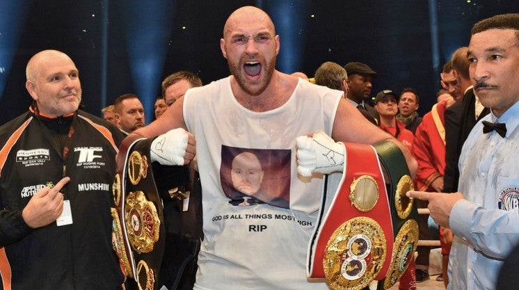 Tyson Fury celebrando una victoria con sus títulos 