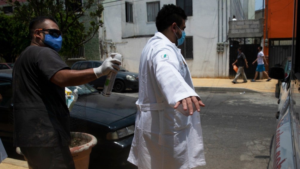 Trabajador desinfecta a un colega de la salud