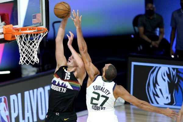 Nikola Jokic intenta anotar sobre Rudy Gobert