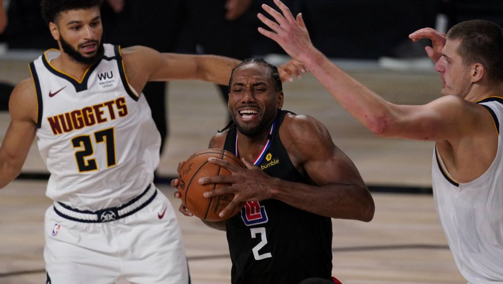 Kawhi Leonard, de los Clippers de Los Ángeles, avanza entre Jamal Murray