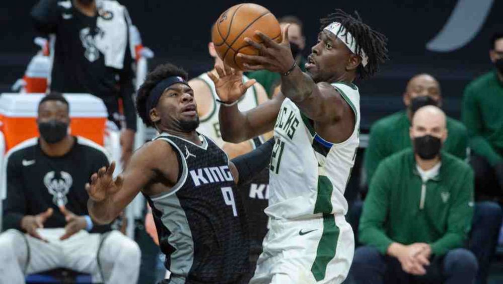 Jrue Holiday, de los Bucks de Milwaukee, intenta disparar frente a Terrence Davis