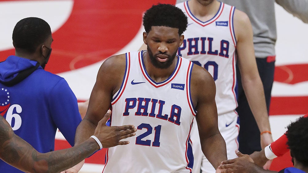 Joel Embiid  es felicitado por sus compañeros 