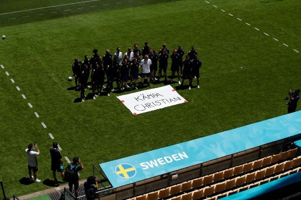 Equipo sueco durante entrenamiento posa junto a un cartel que dice "Mejórate Christian" 