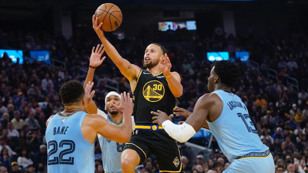 Stephen Curry saltando entre Desmond Bane, Ziaire Williams, y Jaren Jackson Jr. 